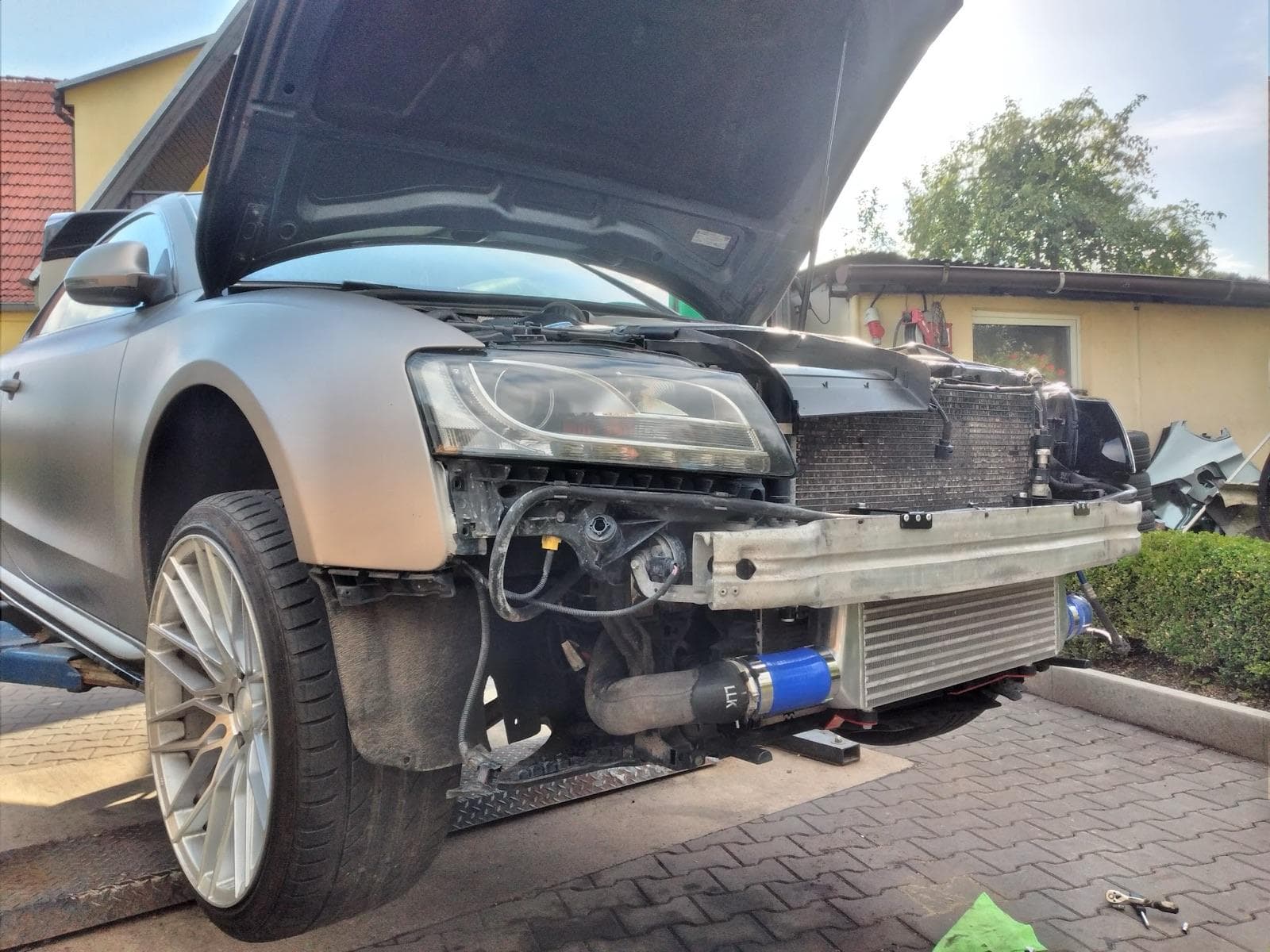 Audi ze zdemontowanym przednim zderzakiem i odsłoniętym intercoolerem na placu przed warsztatem