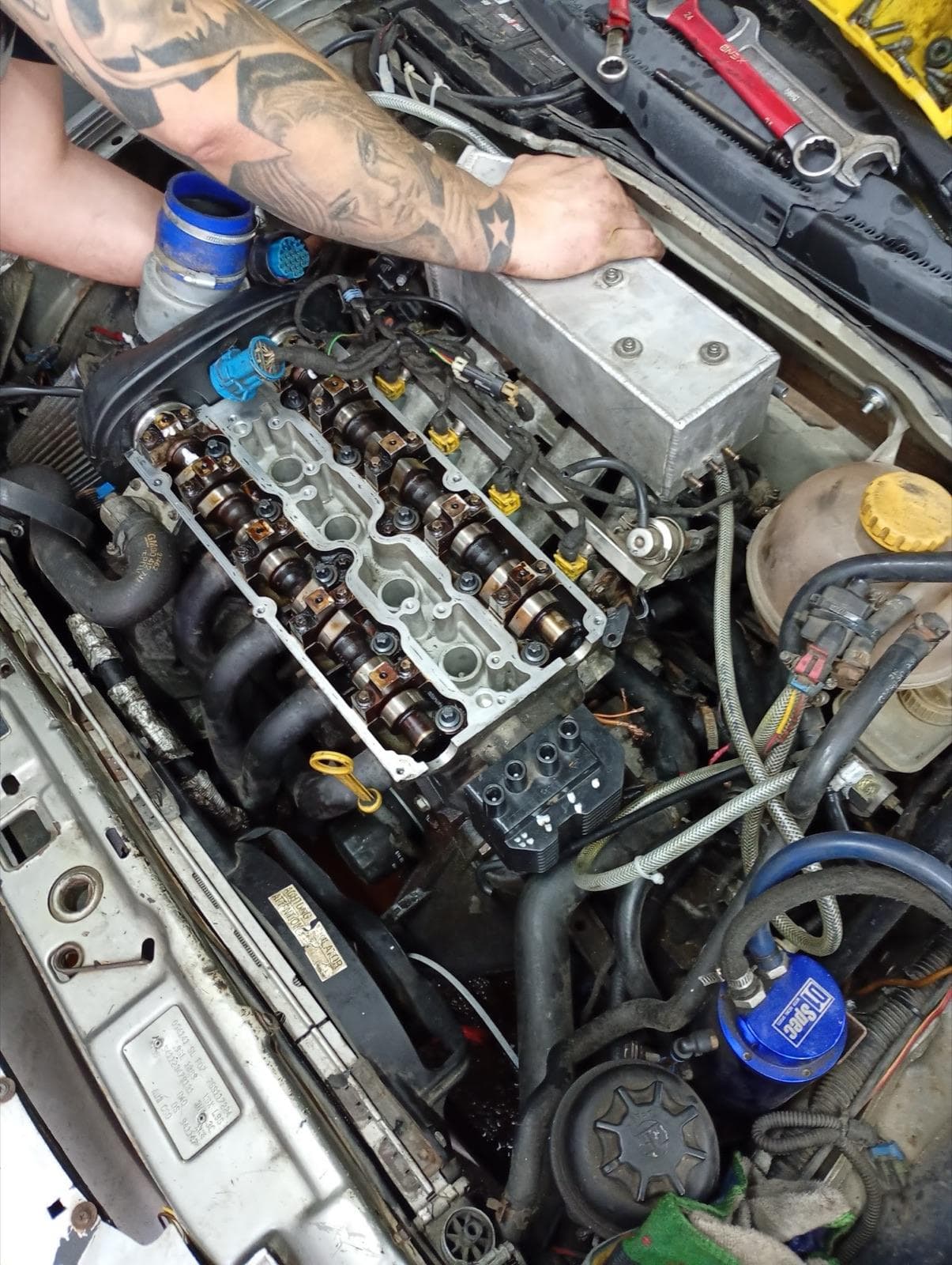 Mechanik pracuje przy silniku z odkrytą głowicą i wałkami rozrządu